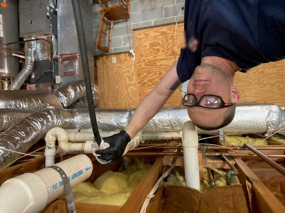 BF Plumbing & Drain technician inspecting overhead drain lines on a service call