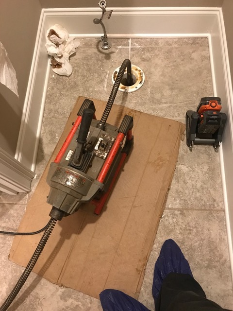 RIDGID K-series drum machine staged on cardboard to clear a bathroom drain line