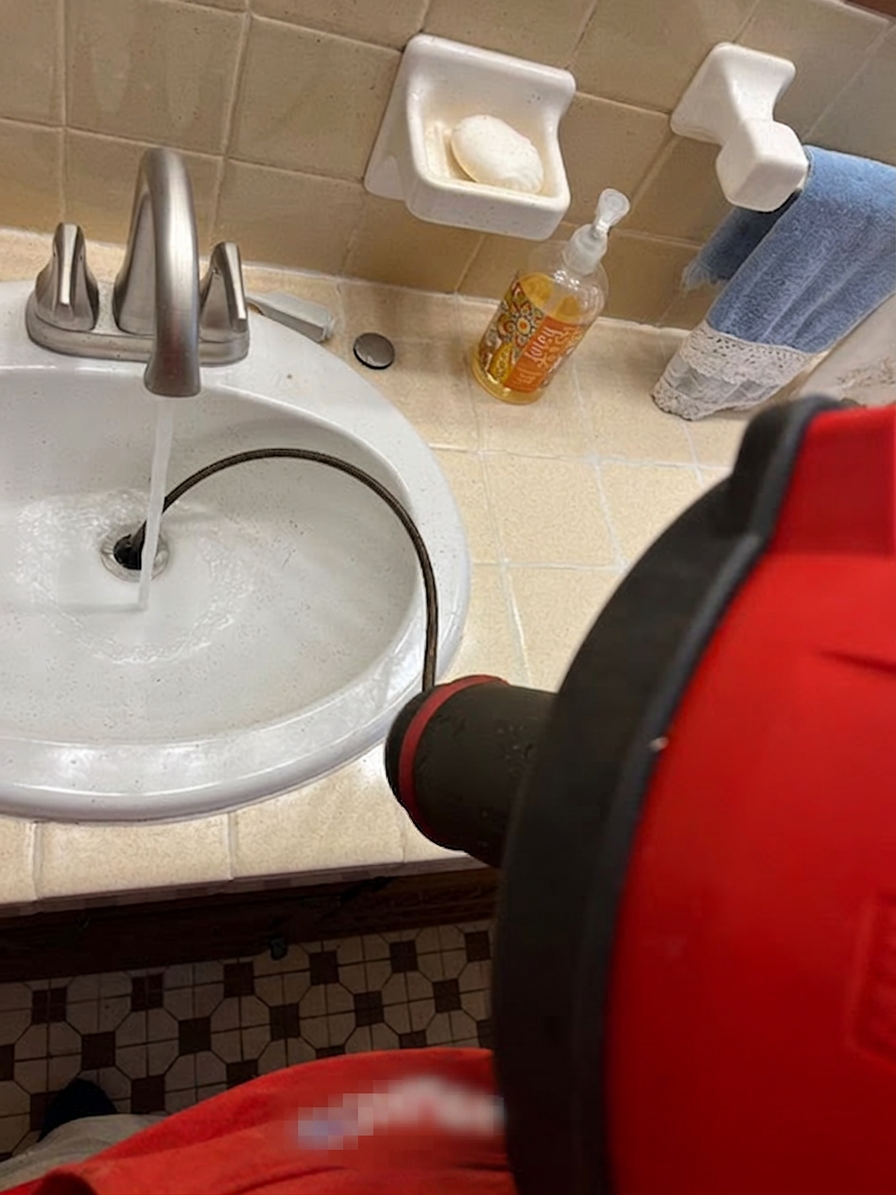 Drain machine running a cable through a slow-draining bathroom sink