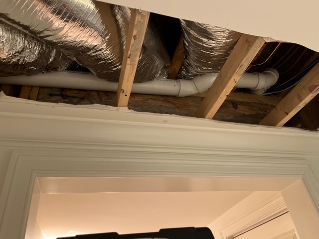 Ceiling opened to expose PVC drain lines and HVAC ducts during a leak detection job